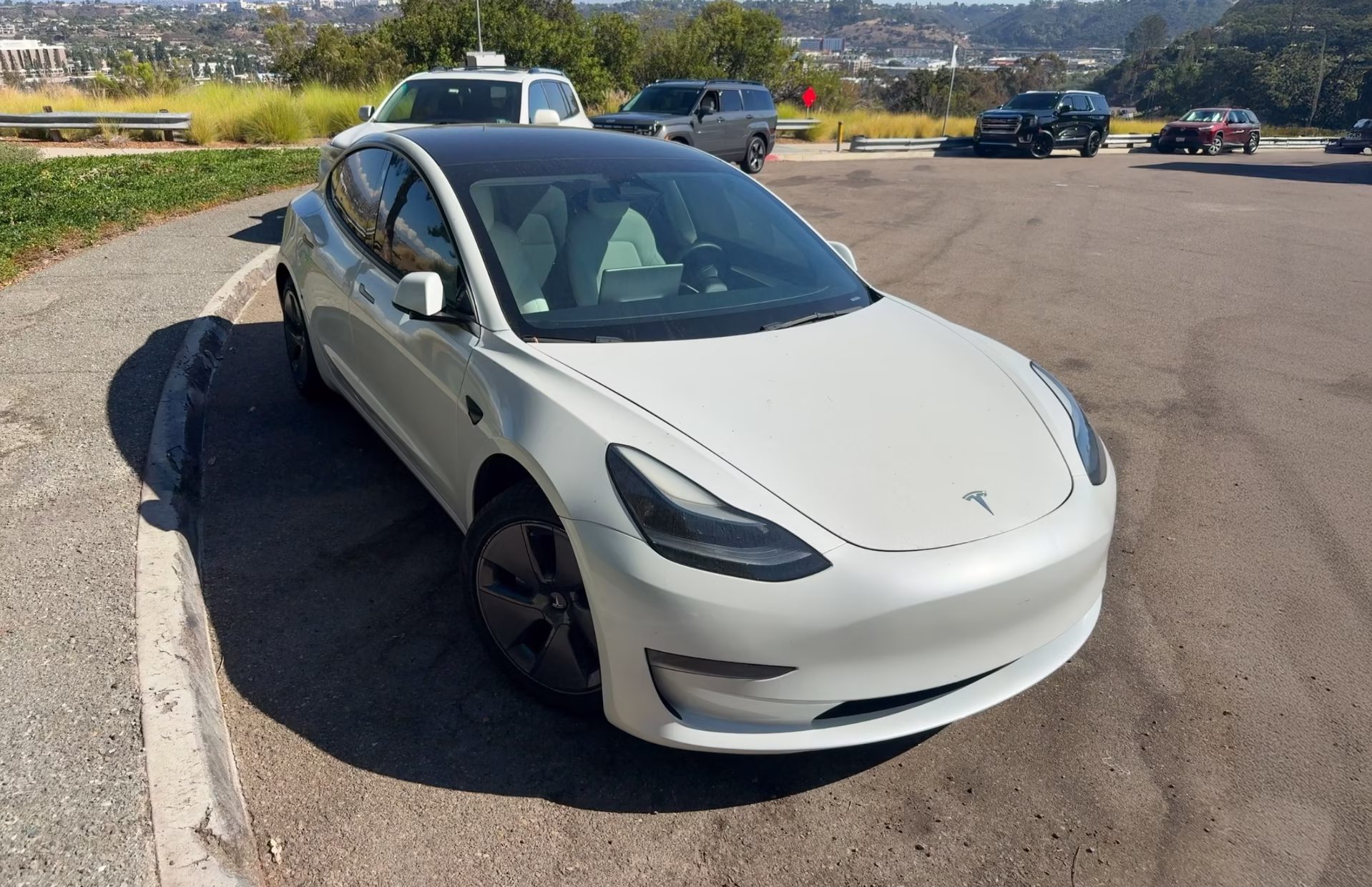 White Tesla Model 3 parked at a hillside lot